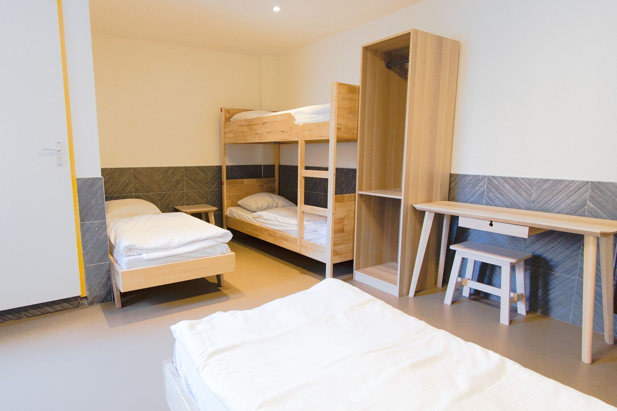 Une chambre de dortoir avec des lits superposés, un bureau et une chaise.