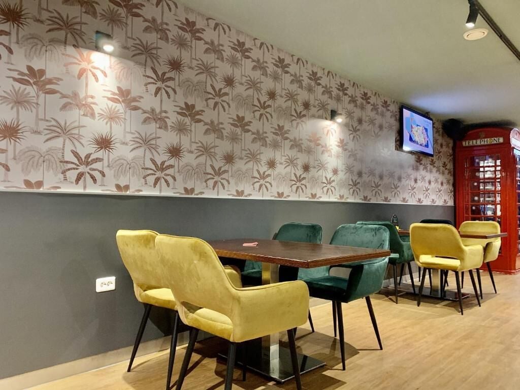 A dining area with a wooden table and chairs, a patterned wall, and a red telephone booth.