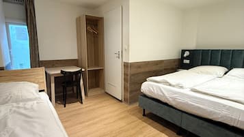 Ein Hotelzimmer mit zwei Betten, einem Schreibtisch und einem Kleiderschrank.