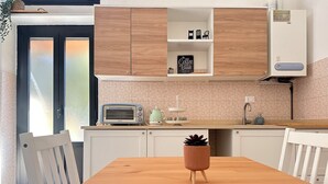 Une cuisine moderne avec des meubles blancs, une table en bois et un grille-pain vintage.