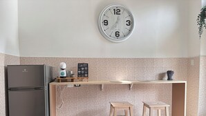 Une cuisine équipée d’un réfrigérateur, d’une machine à café, d’une horloge et d’un tableau noir servant de menu.