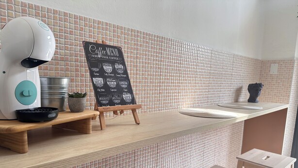 Un espace dédié au café, comprenant un tableau affichant le menu, une machine à café et une petite table.