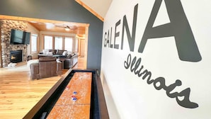 A billiards table in a room with a stone fireplace, leather sofas, and a large wall sign reading "GALEN Illinois".