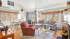 A spacious living area with a sofa, armchair, dining table, and large windows. - Amazing Lake Views! Close to Resort! Patio, Fireplace & Dog Friendly! (Galena)