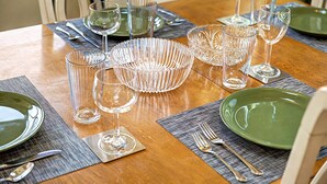 A dining table set with clear glassware, green plates, and silverware on placemats. - Amazing Lake Views! Close to Resort! Patio, Fireplace & Dog Friendly! (Galena)