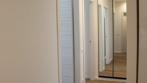 A hallway with white walls and wooden flooring, leading to a mirrored closet door. - Holiday home catania 5km from the center relaxation apartment complete kitchen
 (Sicilia)