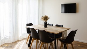 A dining area with a wooden table, black chairs, and a vase with dried plants. A flat-screen TV is mounted on the wall. - Holiday home catania 5km from the center relaxation apartment complete kitchen
 (Sicilia)