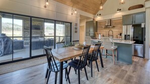 Una cocina amplia con electrodomésticos modernos, un comedor con mesa y sillas de madera, y grandes ventanas que ofrecen vistas al exterior.