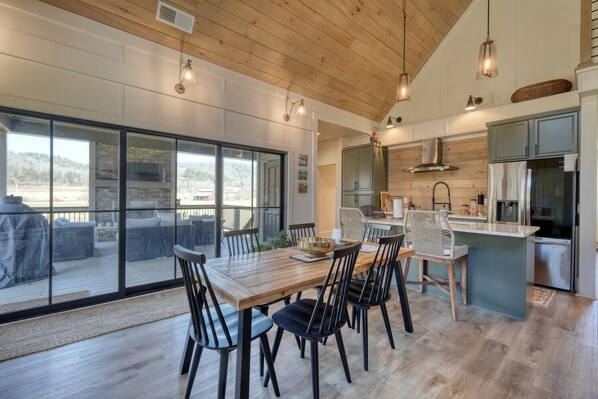 Una cocina amplia con electrodomésticos modernos, un comedor con mesa y sillas de madera, y grandes ventanas que ofrecen vistas al exterior.