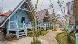 A row of blue-roofed cottages with a central pathway, surrounded by greenery. - D'yuki Huts Lembongan (Lembongan Island)