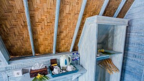 A room with a woven ceiling, a small shelf with a kettle, cups, and a tissue box, and a power outlet. - D'yuki Huts Lembongan (Lembongan Island)