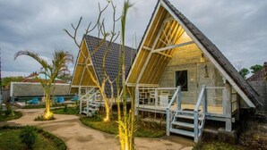 A wooden cabin with a sloped roof, a porch with steps, and a pathway leading to it. - D'yuki Huts Lembongan (Lembongan Island)