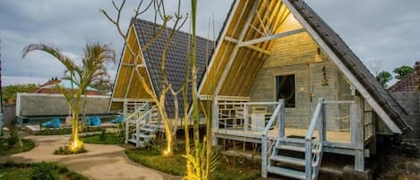 A wooden cabin with a sloped roof, a porch with steps, and a pathway leading to it.