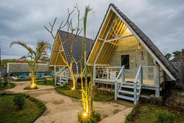 A wooden cabin with a sloped roof, a porch with steps, and a pathway leading to it.