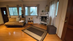 Um quarto espaçoso com uma cama grande, uma mesa pequena, uma lareira e vista para o exterior.