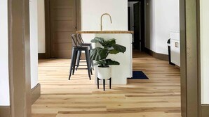 Una cocina moderna con una isla central, taburetes de bar y una lámpara colgante.