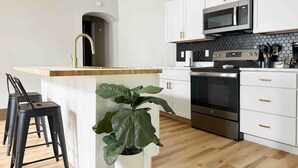Una cocina moderna con armarios blancos, encimera negra y electrodomésticos de acero inoxidable.