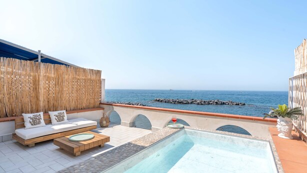 Eine Dachterrasse mit Pool, Sitzgelegenheiten und Meerblick.