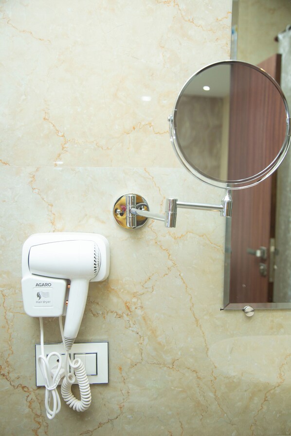 A hair dryer mounted on a wall with a mirror above it. - PARK EASTERN HOTEL (Kolkata)