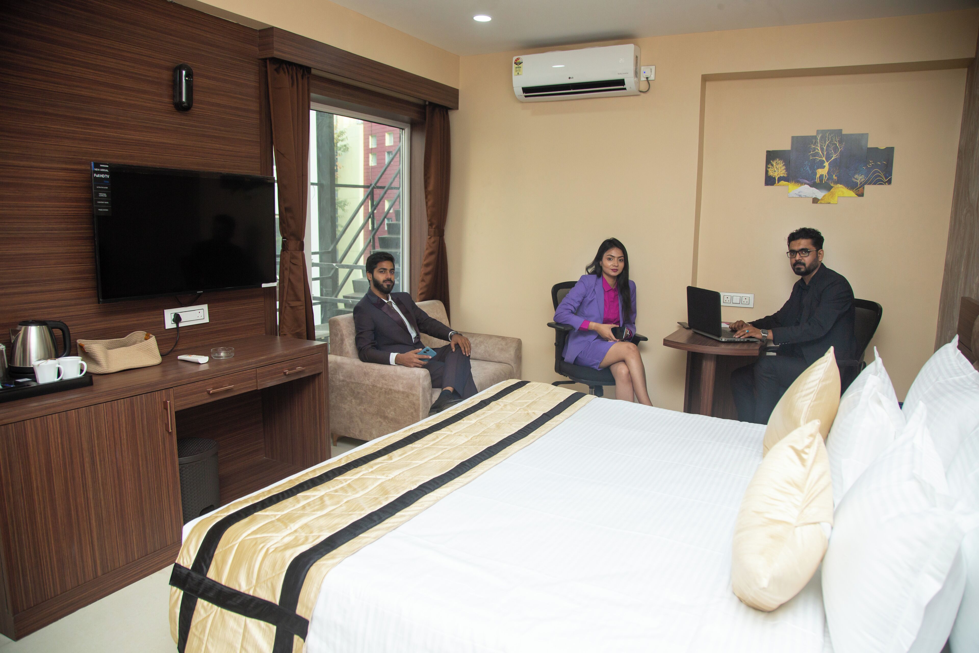 A hotel room with a bed, a desk, a television, and a window with a view of buildings.