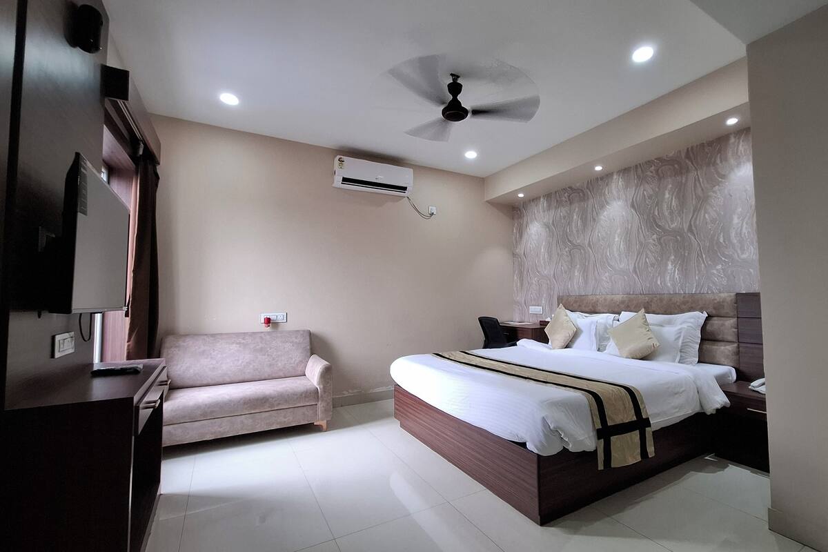 A modern bedroom with a bed, a chair, a desk, and an air conditioning unit.