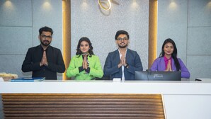 Four people standing at a reception desk in a modern lobby with a textured wall and a wooden panel design. - PARK EASTERN HOTEL (Kolkata)