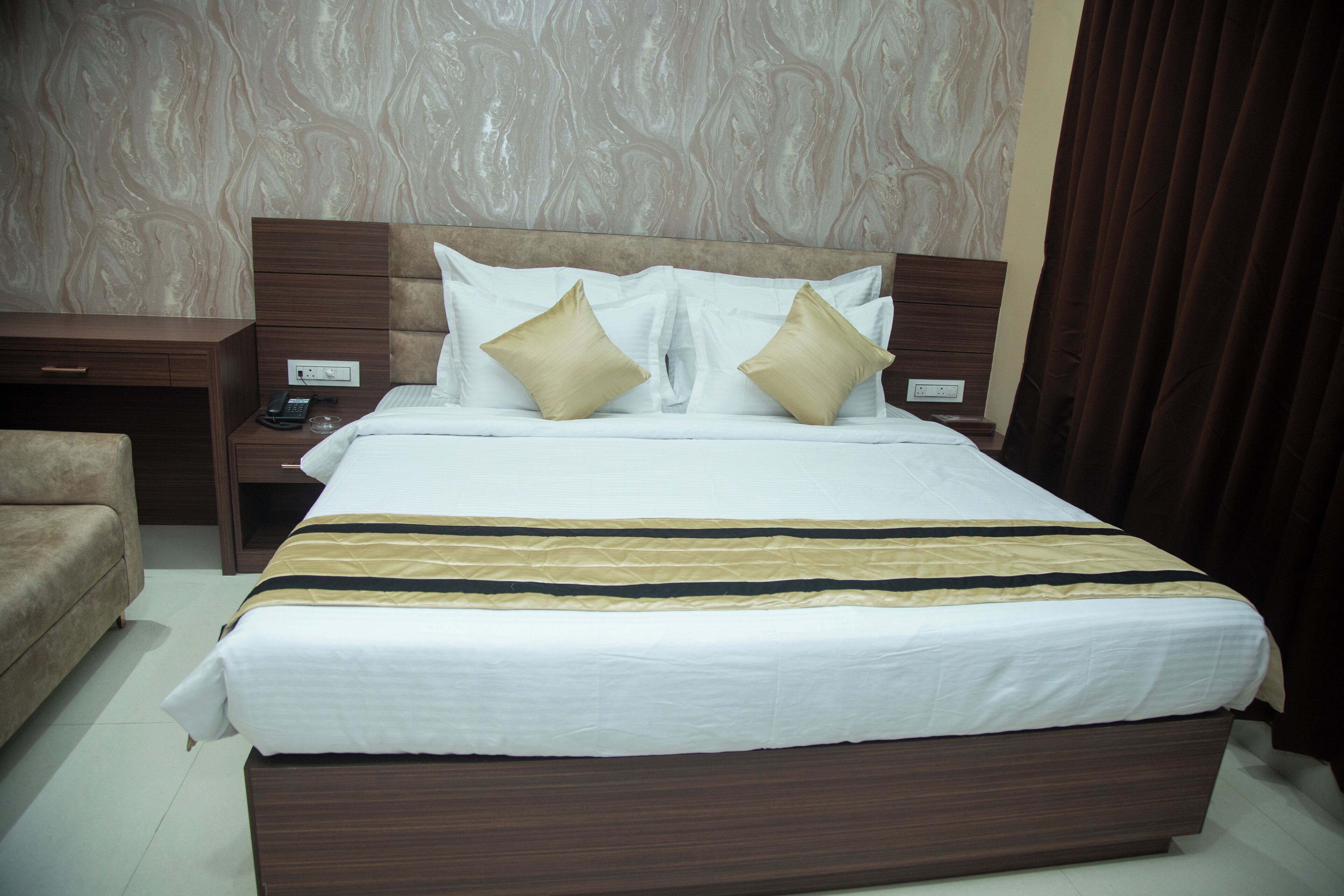 A neatly made bed with a striped bedspread, two bedside tables with lamps, and a brown headboard.