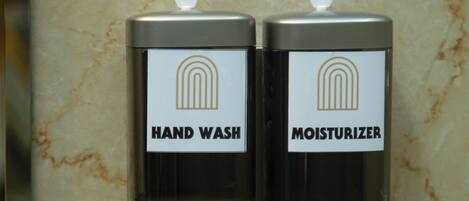 Due erogatori, uno con l'etichetta 'HAND WASH' e l'altro 'MOISTURIZER', fissati a una parete in marmo.
