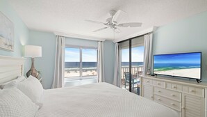 A bedroom with a bed, a ceiling fan, a television, and a view of the beach. - Summerchase 307 by Liquid Life (Orange Beach)