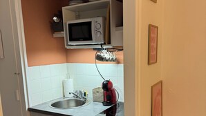 Una cocina compacta equipada con microondas, hervidor y nevera pequeña.