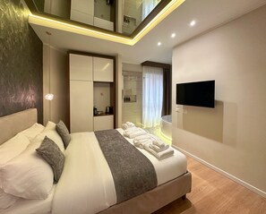 A modern hotel room with a large bed, a TV mounted on the wall, and a bathroom visible through a glass door. - Suite with jacuzzi near Vatican (Room 1) (Roma)