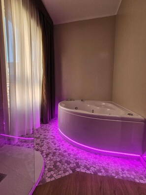 Casa de banho moderna com uma banheira independente, soalho com padrão de pedras e iluminação LED roxa.