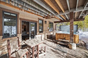 A covered outdoor area with a wooden bench, a table, and a hot tub.