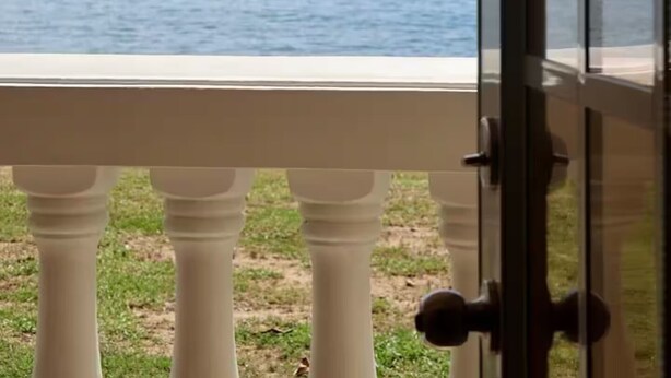 Une vue depuis un balcon avec une porte vitrée, donnant sur une étendue d’eau.