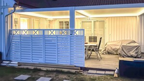 A covered patio area with a table and chairs, a covered sofa, and a blue gate. - 5 Star Holiday Home in Engelsviken (Fredrikstad)