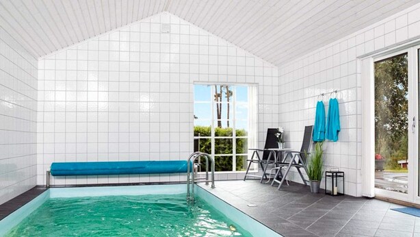 A swimming pool with a blue bench, a small table with a chair, and a potted plant. - 5 Star Holiday Home in Engelsviken (Fredrikstad)