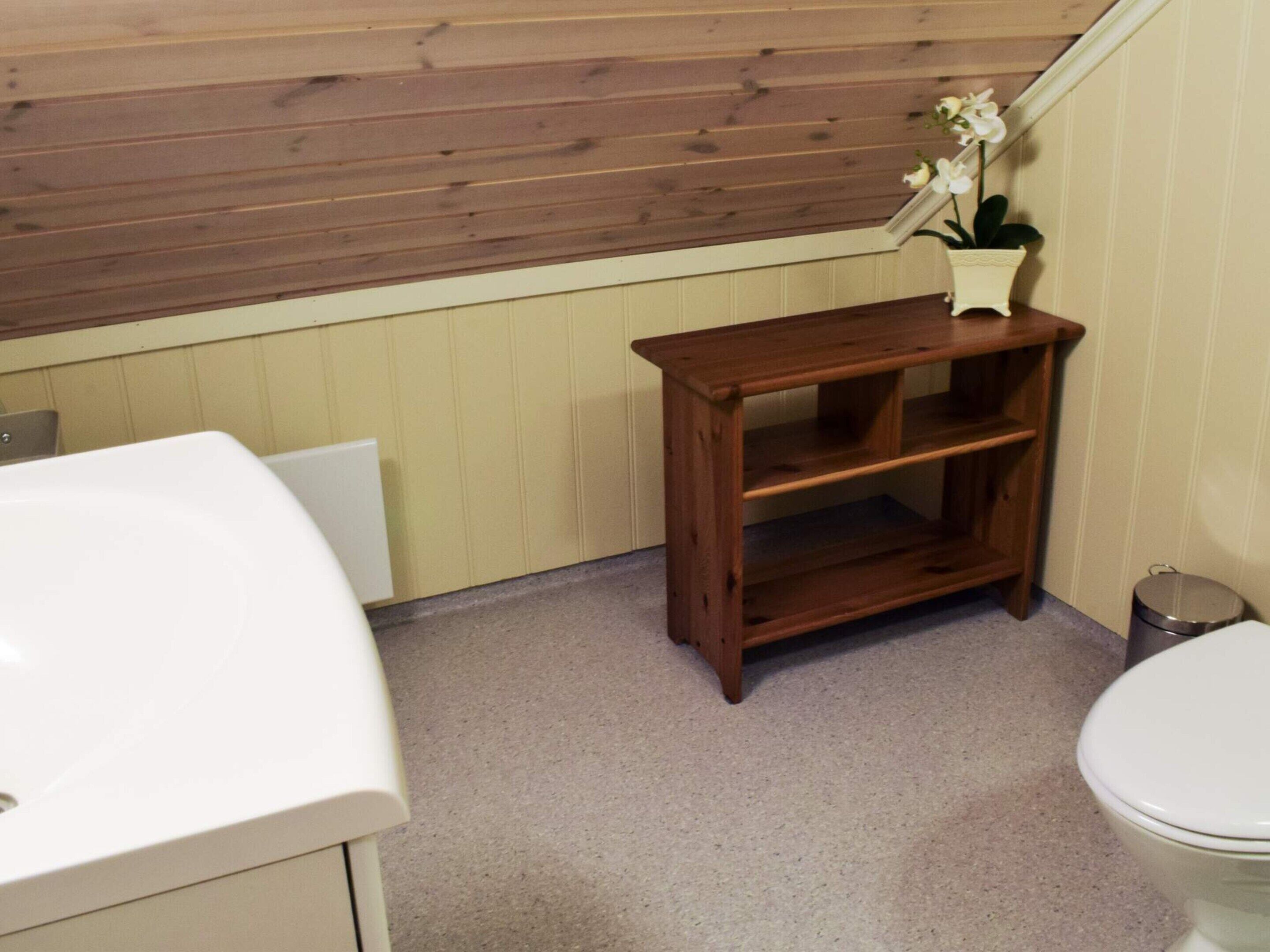 Een badkamer met een houten plank, een witte wastafel en een toilet.