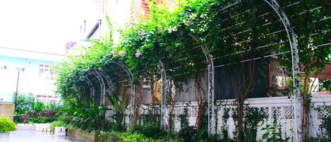 A covered outdoor area with potted plants and a white fence.