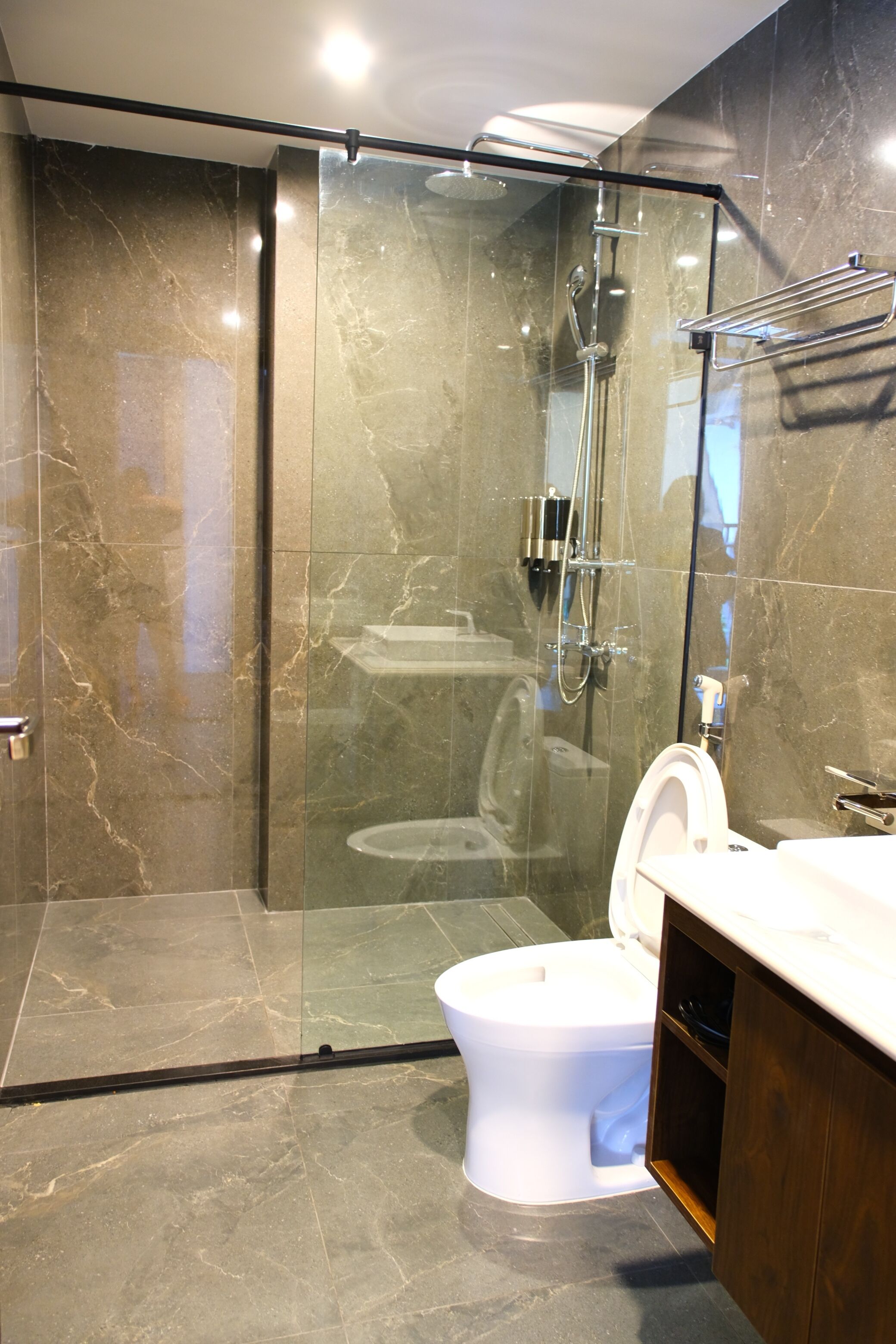 A modern bathroom with a glass-enclosed shower, a white toilet, and a wooden vanity.