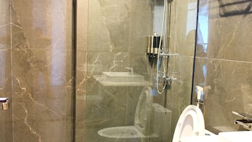 A modern bathroom with a glass-enclosed shower, a white toilet, and a wooden vanity.