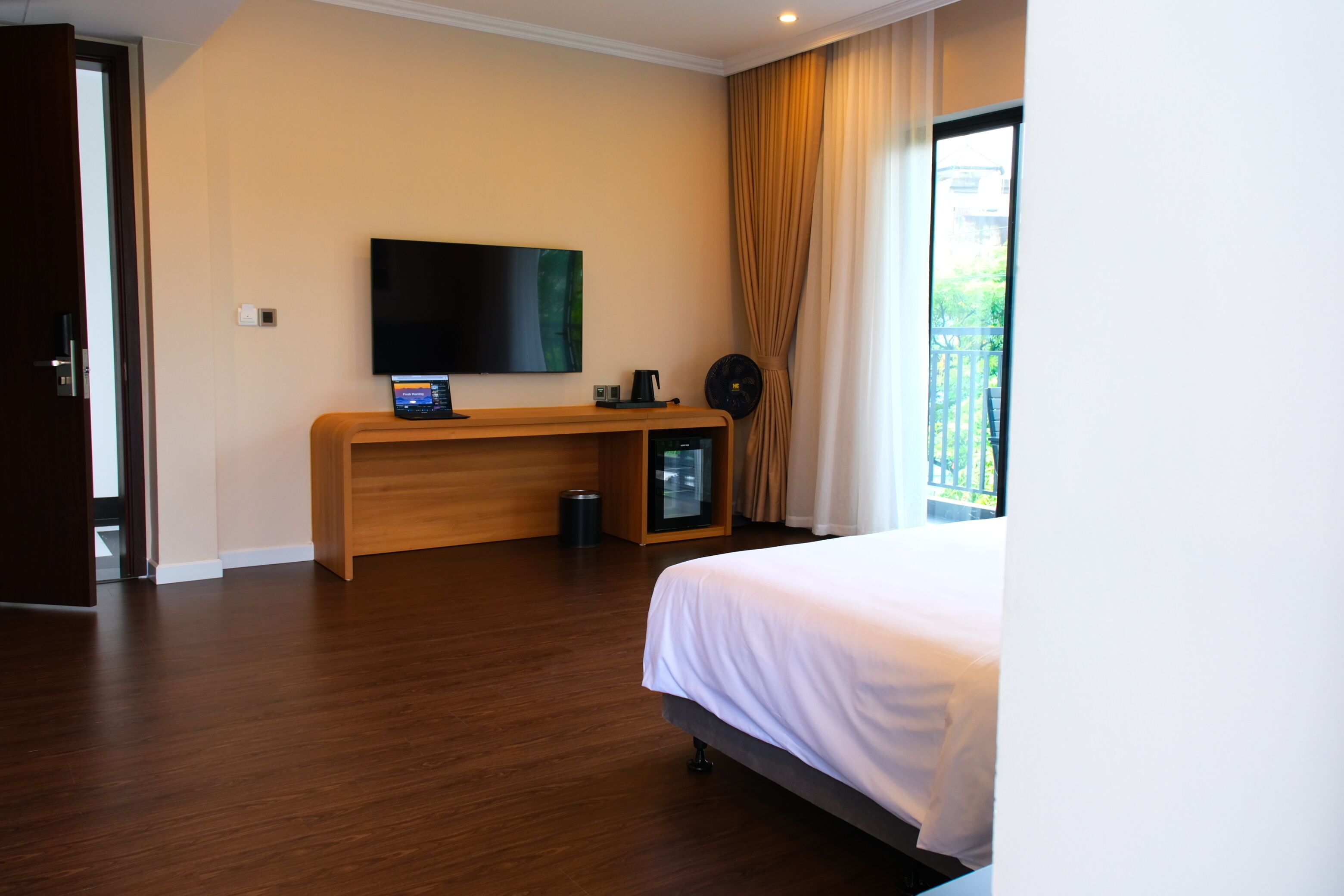 Een hotelkamer met een bed, een televisie, een bureau met een laptop en een kleine verwarming.