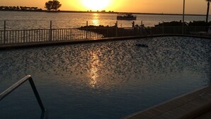 Ein Sonnenuntergang über einem Gewässer mit einer Anlegestelle und einem Boot.