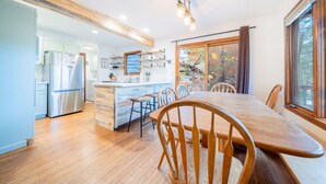A modern kitchen with a wooden island, stainless steel appliances, and a dining area with a wooden table and chairs. - Walk Into National Park! River Access & Fishing (Estes Park)