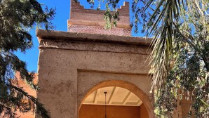 Un arco de entrada con una puerta de madera, un farol colgante y una vista del interior a través del arco.