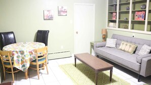 A living room with a dining table, chairs, a sofa, and a coffee table. - SPACIOUS ECO-FRIENDLY SUITE with KITCHEN ON PARK (Halifax)