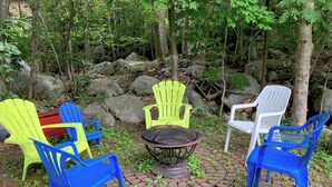 Outdoor seating with plastic chairs and a fire pit in a wooded area. - SPACIOUS ECO-FRIENDLY SUITE with KITCHEN ON PARK (Halifax)