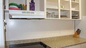 A kitchen with a granite countertop, a black induction cooktop, and white cabinetry. - SPACIOUS ECO-FRIENDLY SUITE with KITCHEN ON PARK (Halifax)