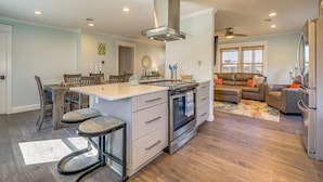 A modern kitchen with a central island, an oven, and a stainless steel range hood. - Peaceful Getaway Close to Loop, Beach, Dining (Wrightsville Beach)