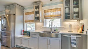 A modern kitchen with stainless steel appliances, white cabinetry, and a window with a view. - Peaceful Getaway Close to Loop, Beach, Dining (Wrightsville Beach)