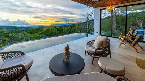 Un espace extérieur moderne, aménagé avec des meubles en osier et offrant une vue sur le paysage.